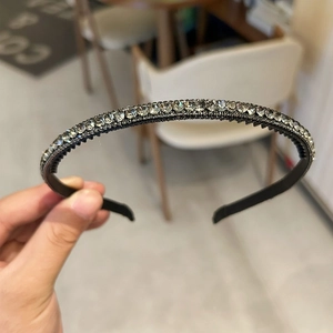 Detailed close-up of a slim black headband with sparkling rhinestones and non-slip inner teeth