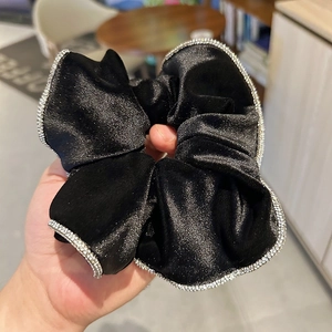 Detail view of premium black velvet scrunchie with sparkling rhinestone edge trim decor