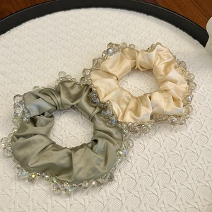 Elegant olive and champagne crystal beaded silk scrunchies set on a woven tray