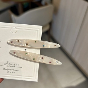 Fermagli per capelli in acetato con motivo marmoreo e strass colorati su carta