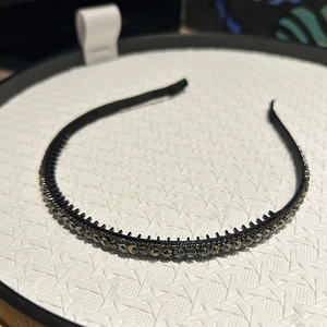 Detail view of the black slim headband with smoky grey rhinestones and non-slip inner teeth