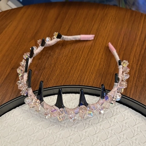 Détail d'un serre-tête en cristaux roses avec pointes noires et ruban de satin élégant