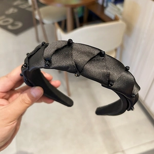 Detail of a handmade black padded headband featuring crystal beads and satin texture