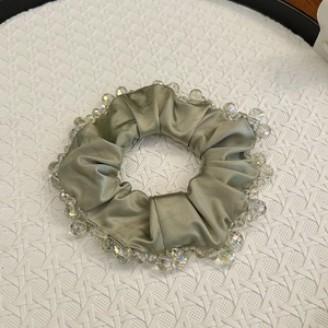 Detail of elegant dark green silk scrunchie featuring clear faceted crystal bead trim