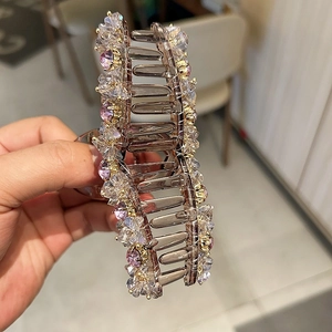 Close-up of a large hair claw clip with shimmering crystals in a detailed hand-held view