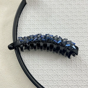 Detail of banana hair clip featuring sparkling blue and grey crystals on black base