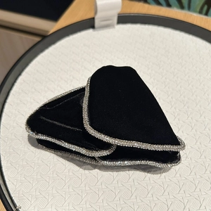 Close-up of black velvet hair clips featuring elegant silver rhinestone edges on a tray