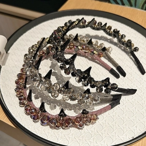 Detailed view of luxury rhinestone wave headbands with punk-style spikes on white tray