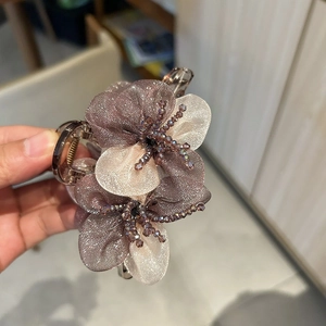 Close-up of elegant organza flower hair claw clip with crystal beads and sheer petals