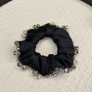 Detailed shot of black satin scrunchie with sparkling multifaceted crystal beads