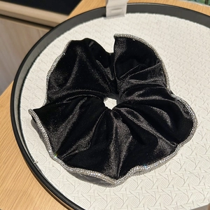 Detail of black velvet scrunchie with sparkling silver rhinestone trim on white display tray