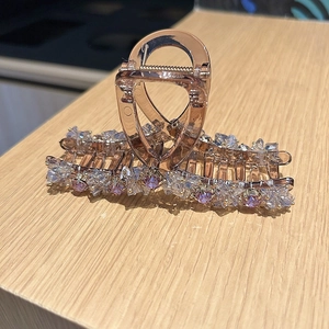 Detail view of large hair claw clip with pink crystals and translucent amber finish