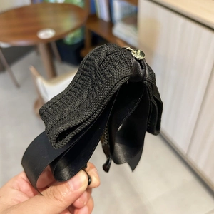 Detailed macro view of black knit bow banana clip with elegant satin texture and gold charm