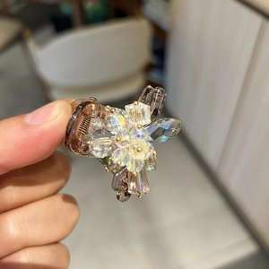 Detailed view of luxury crystal-encrusted mini flower hair claw clip with rhinestones
