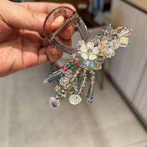 Detail of crystal hair claw clip with purple beads and white flower charms tassel
