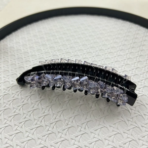 Detail of a large black banana hair clip with light purple crystal beads and glossy finish