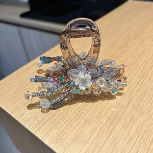 Detail of amber crystal hair claw clip with floral pearl accents on a wooden surface