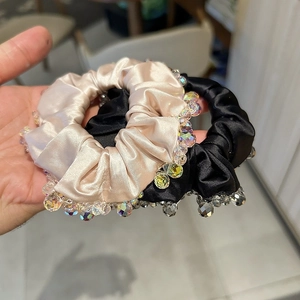 Detail of satin scrunchies with iridescent crystal beads in champagne gold and black