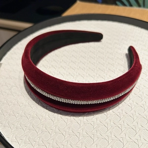 Close-up of burgundy velvet padded headband with sparkling rhinestones on tray
