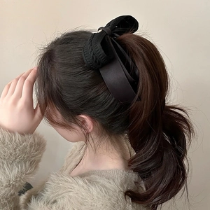 Detail shot of black knitted bow banana clip with satin ribbons on a high ponytail hairstyle