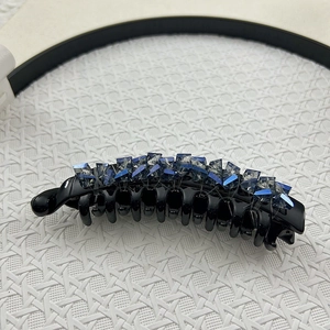 Detailed macro view of an elegant black banana clip featuring dark blue crystal bead accents