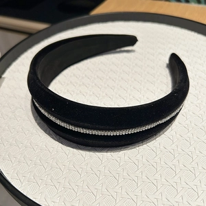 Close-up of black velvet headband with sparkling rhinestones on white tray