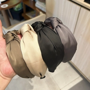 Détail de quatre serre-têtes en satin noués de couleur olive, crème, noir et gris