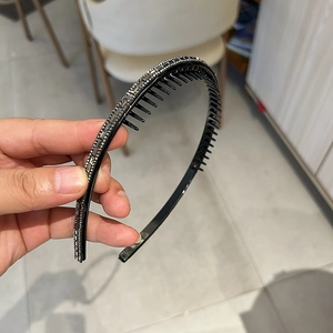 Détail d'un serre-tête noir antidérapant avec strass gris brillants et dents de peigne