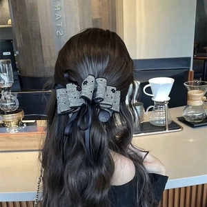 Detail of elegant black and white bow hair clip with long ribbons on a half-up hairstyle