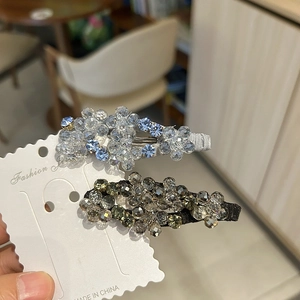 Dettaglio di due fermagli per capelli in cristallo con perline sfaccettate blu e ambra