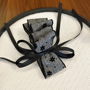 Detailed close-up of a layered black and white ribbon bow clip with floral pattern