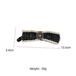 Detail view of tweed bow hair clip with faux pearls and large central gemstone decoration