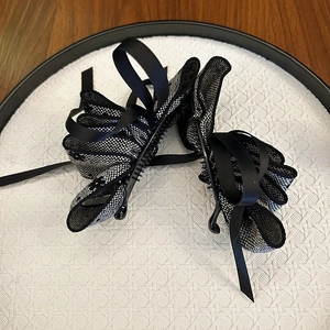 Detail of layered black bow banana hair clip with grid texture on a white decorative plate