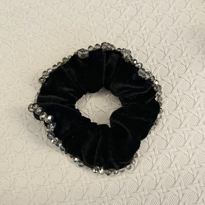 Vue détaillée du chouchou en velours noir avec perles en cristal gris sur tissu blanc