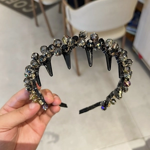Detail showing dark gray crystals and black punk-style rivets on a luxury headband