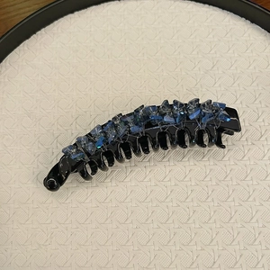 Detailed view of banana hair clip with blue gradient crystals and black glossy teeth