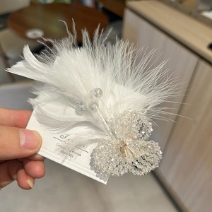 Detailed macro of crystal flower hair clip with soft white feathers and silver finish