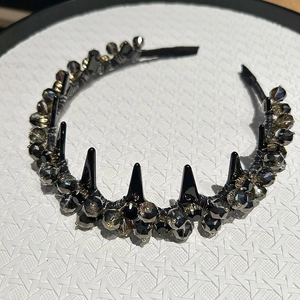 Close-up of black wave headband with sparkling rhinestones and dark gothic spikes