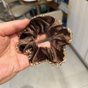 Gros plan détaillé d'un chouchou en velours marron orné de perles de cristal élégantes