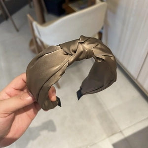 Détail d'un élégant serre-tête en satin marron avec un nœud double épaisseur et fini soyeux