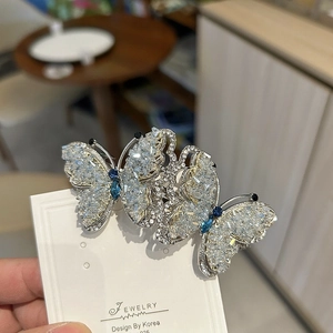 Detailed view of luxury silver butterfly clip with sparkling blue and clear zircons