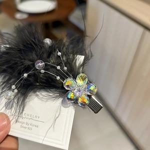 Macro shot of handcrafted black feather hair clip with crystal plum blossom and silver pin