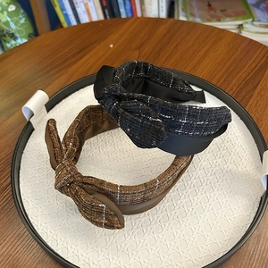 Detail view of retro tweed knot headbands in black and brown with elegant bow decoration