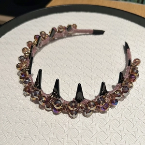 Detail of luxury rhinestone headband with purple crystals and black punk spikes