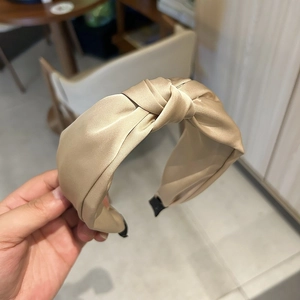 Détail d'un serre-tête en satin doré champagne avec nœud élégant et texture soyeuse lisse
