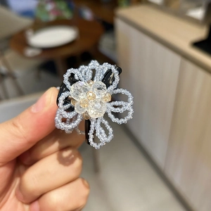 Macro shot of handcrafted flower hair claw featuring sparkling crystals and woven beads