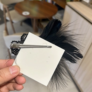 Detail view of black feather hair clip with crystal bead base and metal duckbill fastener