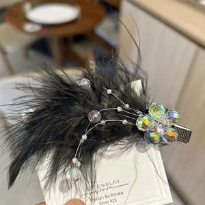 Elegant black feather hair clip with iridescent beads on a minimalist display card