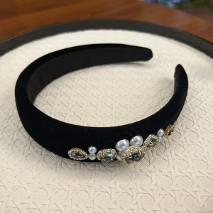 Close-up of black velvet headband featuring white pearls and shimmering square rhinestones