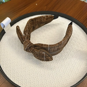 Close-up of brown tweed fabric knotted headband with intricate white stitching details